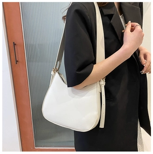 Close-up of a white crescent shoulder bag in PU leather with adjustable strap and metal buckle