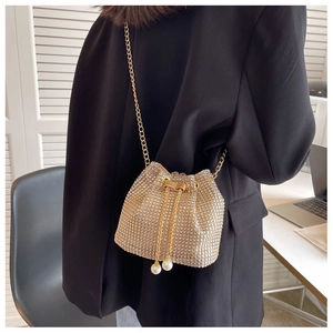 Detailed view of champagne gold rhinestone bucket bag with pearl drawstring and chain strap