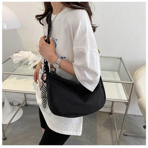 Sac hobo noir minimaliste avec un pendentif à carreaux porté par un mannequin