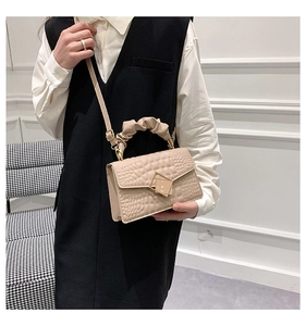 Détail du sac beige à motif crocodile avec poignée plissée et fermoir doré chic
