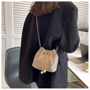 Detail of gold bucket bag with full rhinestones, pearl drawstrings and chain strap