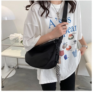 Détail du sac bandoulière croissant en nylon noir avec chaîne et accessoire