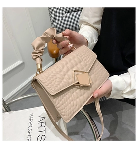 Détail du sac à main beige texture crocodile avec poignée plissée et boucle dorée
