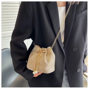 Detail of shimmering gold rhinestone bucket bag with pearl drawstring and chain strap