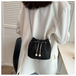 Detail of black rhinestone bucket bag with large pearls and silver chain on model
