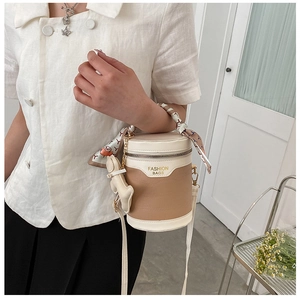 Detail of color-block bucket bag with crocodile texture and floral silk scarf handle