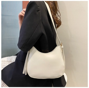 White leather hobo bag worn by model, showing minimalist design and side metal hardware