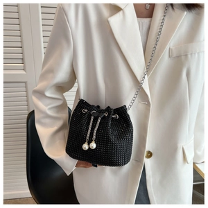 Detailed close-up of a black rhinestone bucket bag with silver chain and pearl drawstrings