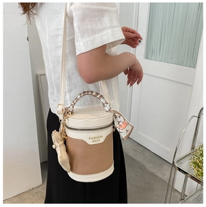 Detail view of cylinder bucket bag featuring crocodile texture and silk scarf handle