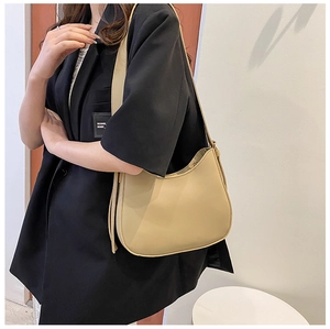 Side view of a khaki saddle bag worn by a model in a black blazer for a chic casual style
