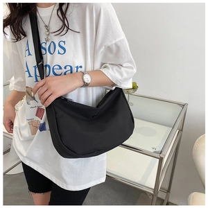 Modèle portant un sac bandoulière demi-lune en nylon noir avec une sangle réglable