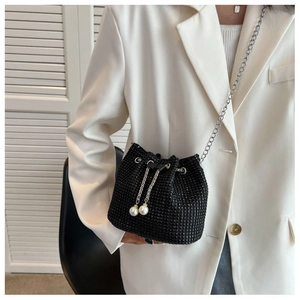 Detail of black rhinestone bucket bag with drawstring pearls and silver chain strap