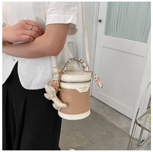 Detail of beige crocodile pattern bucket bag with silk scarf handle and bear charm