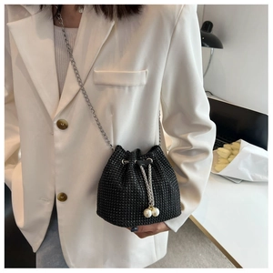 Detail of a black rhinestone drawstring bucket bag with elegant white pearl tassels