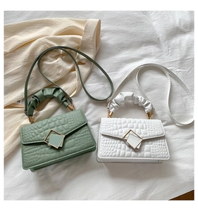 Détail de mini sacs à motif crocodile vert et blanc avec poignées plissées et fermoir métal