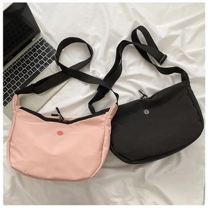 Détail de sacs bandoulière en nylon rose et noir avec bandoulière réglable et logo rond