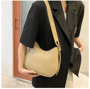 Side view of beige hobo shoulder bag with wide strap and gold buckle on a model