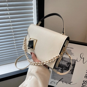 Modern cream leather handbag with black trim and gold clasp on minimalist background