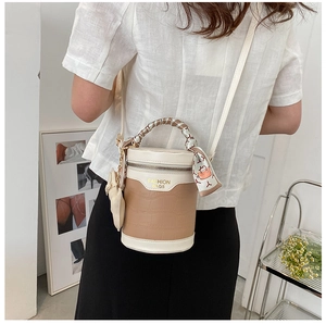 Detail of crossbody bucket bag featuring crocodile texture and silk scarf handle