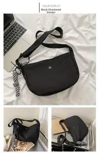 Détail du grand sac bandoulière en nylon noir avec pendentif à motif damier élégant