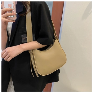 Detail of khaki hobo bag with wide strap worn over a black blazer for daily style