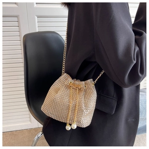 Detail of champagne gold rhinestone bucket bag with chain strap and pearl drawstring