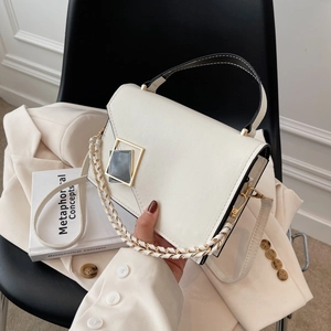 Minimalist white flap crossbody bag with geometric metal buckle on a modern chair