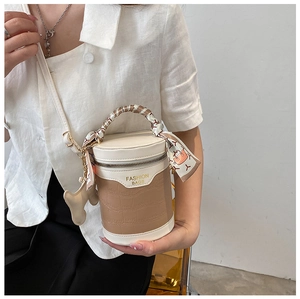 Detail of crossbody bucket bag with crocodile texture, scarf handle and charm