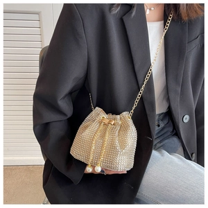 Detail of gold rhinestone bucket bag featuring elegant pearl drawstring and chain strap