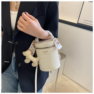 Detail of cream bucket bag with crocodile texture, silk scarf handle and dog charm