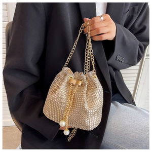 Close-up of golden rhinestone bucket bag with chain handle and pearl drawstring charms