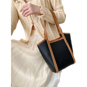 Minimalist large-capacity black and brown leather tote bag worn by a model