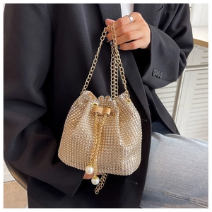 Close-up of golden rhinestone bucket bag featuring metal chain and pearl drawstring charms