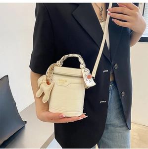 Detail of cream crocodile embossed bucket bag with silk scarf handle and rabbit charm