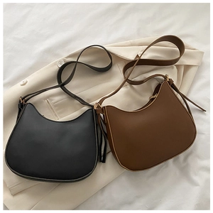 Flat lay of black and brown leather crescent underarm bags with gold hardware detail
