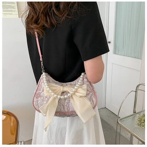 Dettaglio borsa con texture floreale, fiocco di raso, manico di perle e tracolla rosa