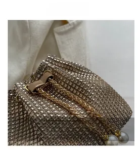 Close-up of champagne gold rhinestone evening bag with chain and pearl details