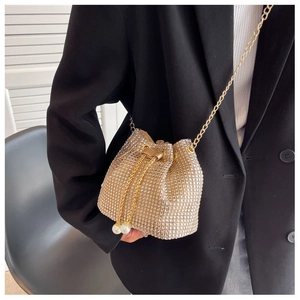 Close-up of gold rhinestone bucket bag featuring elegant pearl drawstring and chain strap
