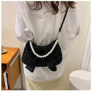 Dettaglio di una borsa sottobraccio nera a pieghe con fiocco grande e catena di perle