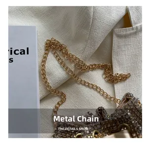 Close-up of golden hardware chain and silver rhinestone bucket bag on white blazer