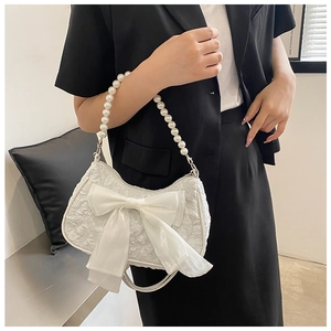 Detail of white pleated handbag with large bow and elegant pearl beaded handle