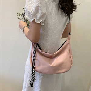 Sac bandoulière rose en forme de lune avec pendentif en damier porté par un mannequin