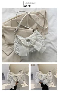 Dettaglio della borsa bianca in jacquard a pieghe con grande fiocco in raso e manico di perle