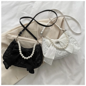 Dettaglio di eleganti borse con fiocco, manici di perle e tessuto testurizzato raffinato