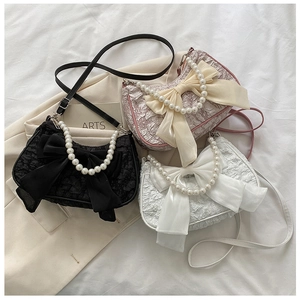 Dettaglio di tre borse con fiocco e manici in perla nei colori nero, rosa e bianco