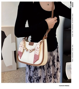 Detail of cream shoulder bag with floral scarf handle and gold chain decoration