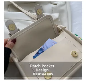 Detail view of the front slip pocket and magnetic snap closure on a cream shoulder bag