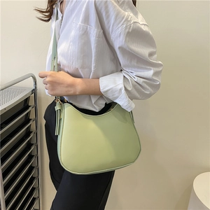 Minimalist mint green half moon crossbody bag shown on a model with white shirt