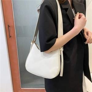 Minimalist white hobo shoulder bag with adjustable strap worn on model over black blazer