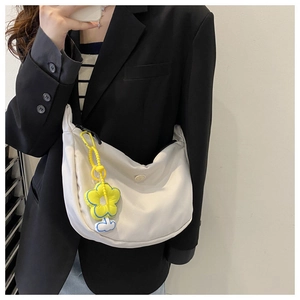 Detail of white nylon crescent crossbody bag with vibrant yellow sunflower charm